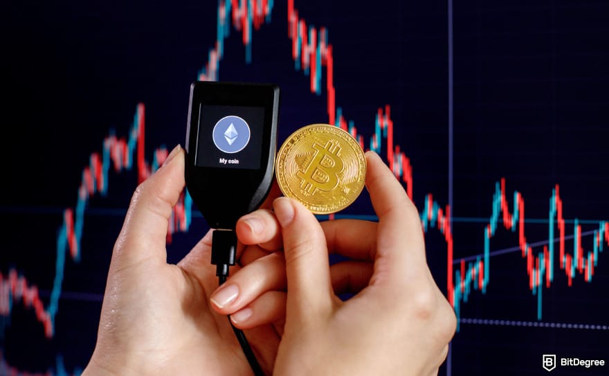 Hardware crypto wallet: a person holding a Trezor wallet and Bitcoin next to price charts. Hardware crypto wallet: a person holding a Trezor wallet and Bitcoin next to price charts.